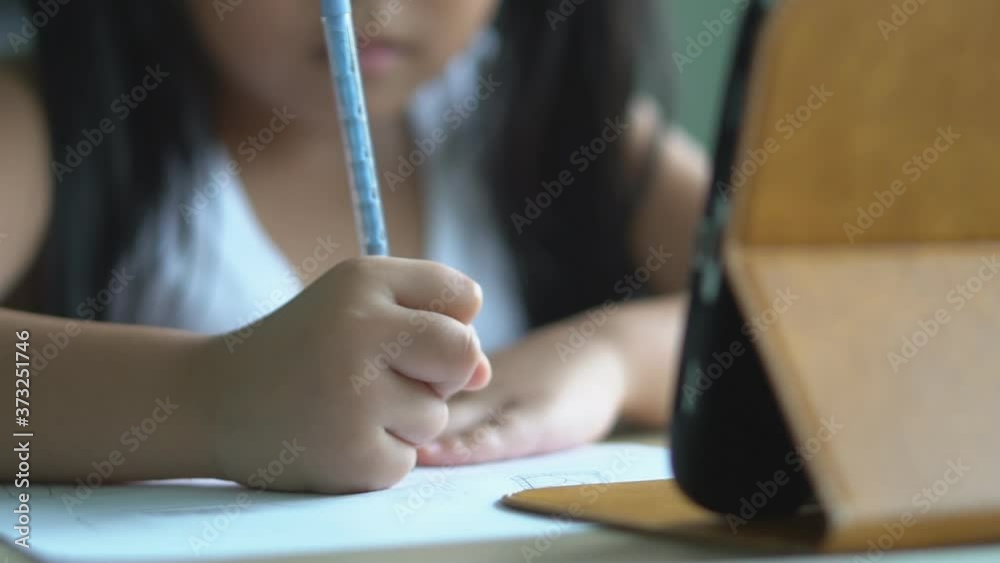 asian child student back to school or kid girl draw or write by pencil and read on computer tablet with doing homework to new idea think or people learn from home and study online on smartphone slow
