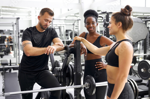 portrait of diverse people talking in gym, pleasant african lady in sportswear attentively listen to friends