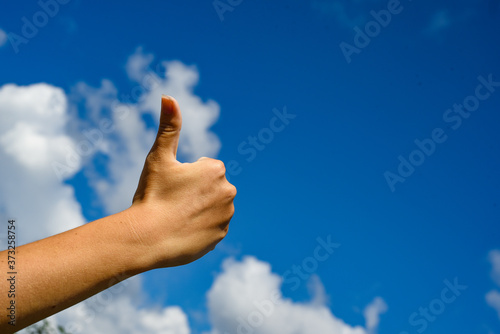 Thumb up in the sky. Hand show thumbs up on a blue sky