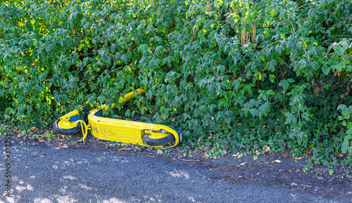 Porzucona zolta hulajnoga.  Zepsuty sprzet transportowy. Kolka w krzakach. 
