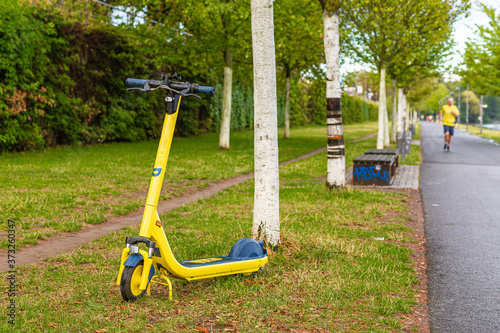 Hulajnoga elektryczna na trawinku. Ekologiczny transport miejski. Sport i rekreacja w miescie.