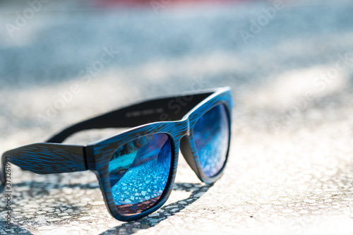 Classic sunglasses model with blue lenses and blue frame in a sunny day closeup . Selective focus
