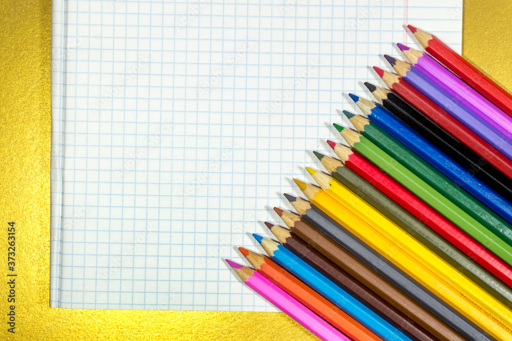 Colored pencils lie on a white notebook sheet. Colored pencils lie on a white notebook sheet.