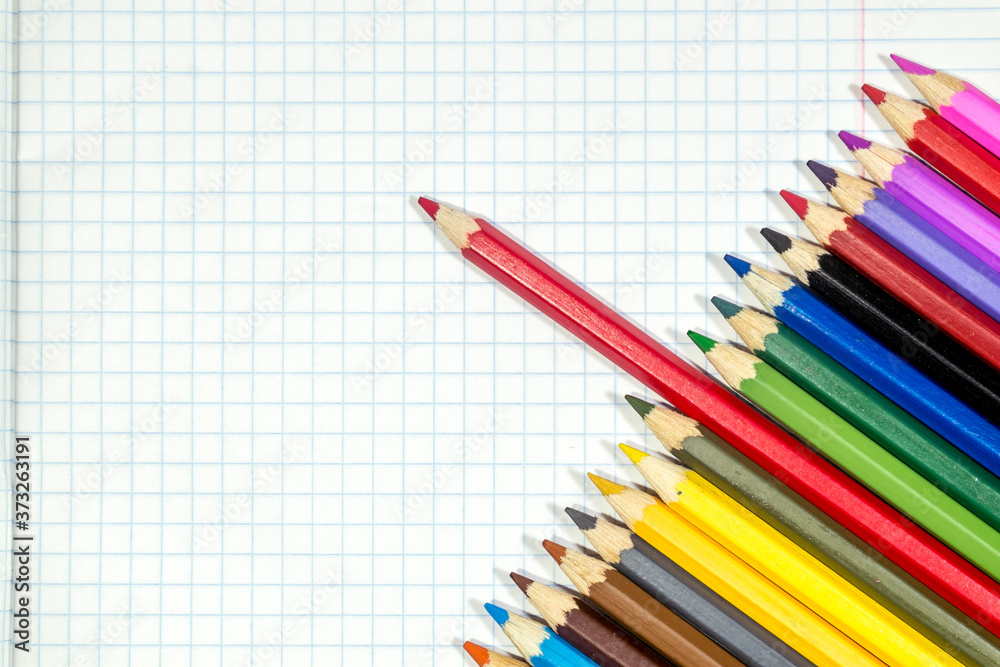 Colored pencils lie on a white notebook sheet. Colored pencils lie on a white notebook sheet.