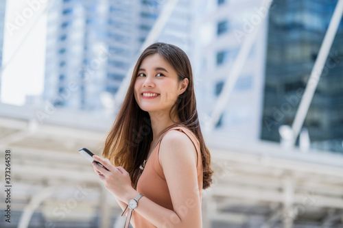 Obraz na płótnie Young Asian woman using smart mobile phone in outside big city at Covid19 outbreak, Infection and Pandemic, commuter and transportation, social distancing and new normal concept w salonie