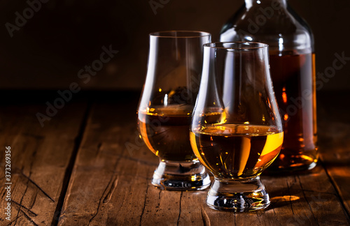 Scotch Whiskey without ice in glasses and bottle, rustic wood background, copy space