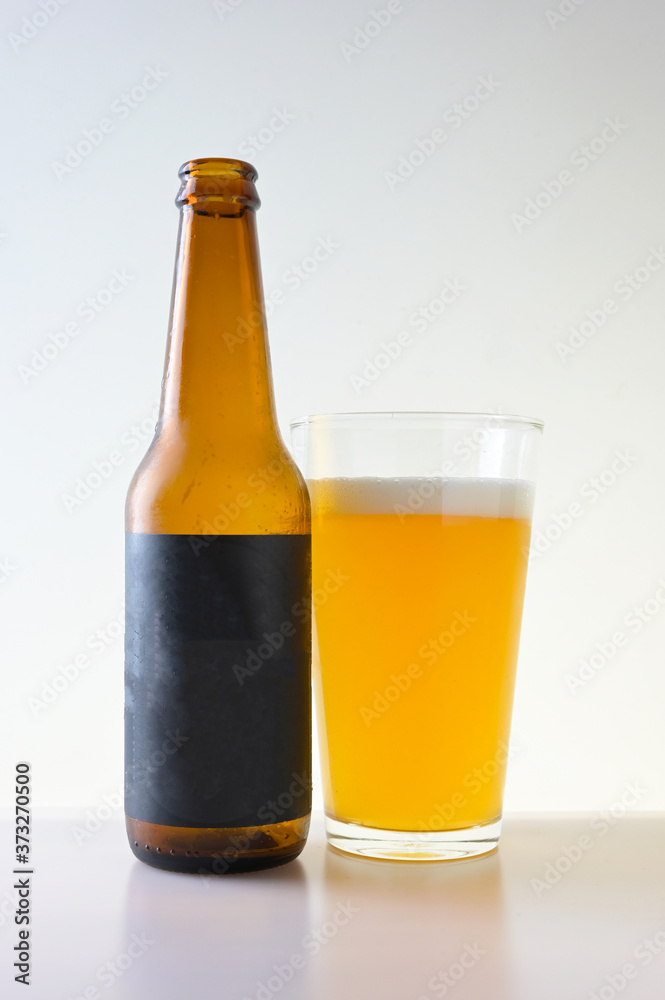 Glass and bottle of beer on white background with black blank label Glass and bottle of beer on white background with black blank label