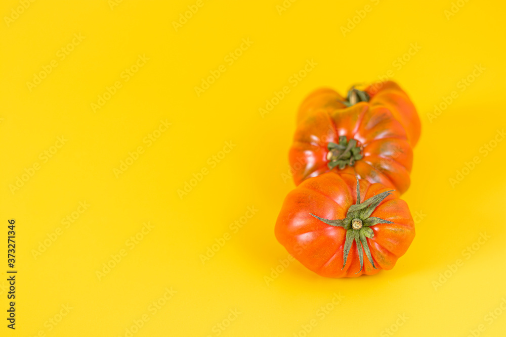 View of beautiful red heirloom tomatoes on yellow background View of beautiful red heirloom tomatoes on yellow background