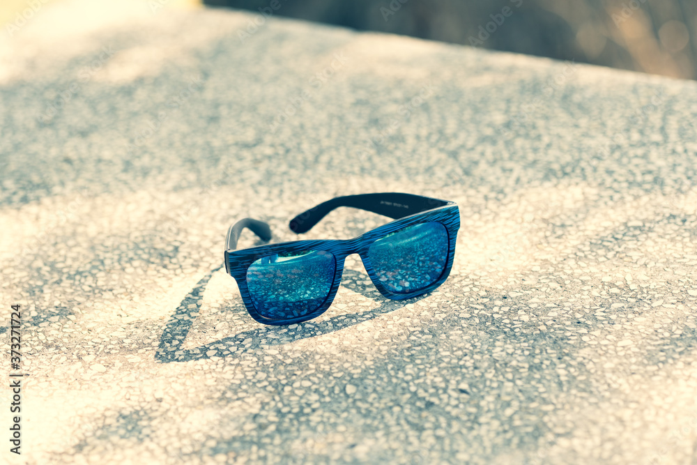 Sunglasses with blue lenses and blue frame in a sunny day closeup . Selective focus Sunglasses with blue lenses and blue frame in a sunny day closeup . Selective focus
