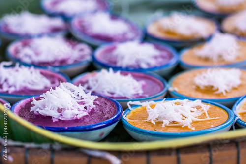 Thai dessert garnished with grated coconut./ The dessert is yellow and purple in the cup.