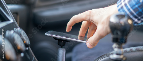 male driver sitting in the car and using the phone with navigation