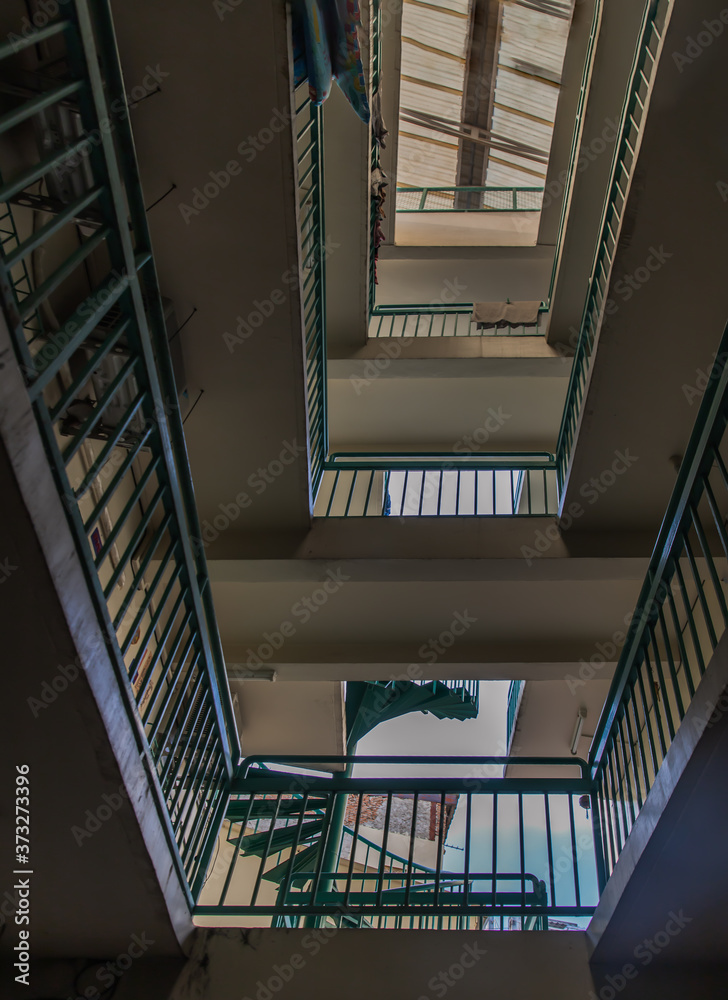 Looking up from under view upstairs walkway of an old apartment building with green metal rails and skylight. Selective focus. Looking up from under view upstairs walkway of an old apartment building with green metal rails and skylight. Selective focus.