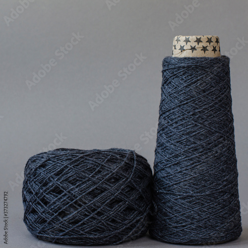 cone and ball of gray wool yarn on light gray background