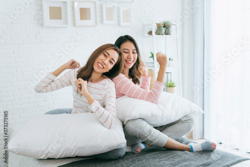 Two pretty best friends forever girlfriend talk, hug and laugh together on bed at cozy home relation fall in love. Lesbian couple homosexual happy lifestyle on bed. LGBTQ relation lifestyle concept. © aFotostock