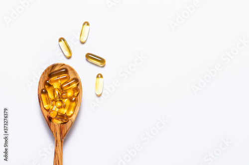 Billede på lærred Omega 3 cod liver oil capsules in the wooden spoon on white background with copy space for your design