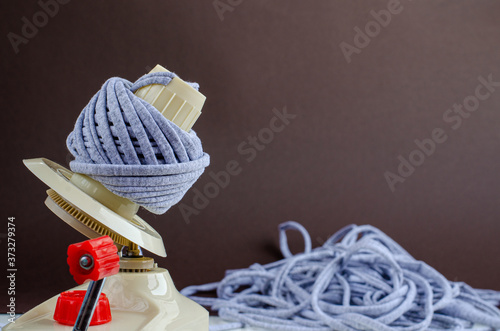hand plastic wool winder at work, gray yarn ball, brown background. prepair for knitting, crochet. handmade concept