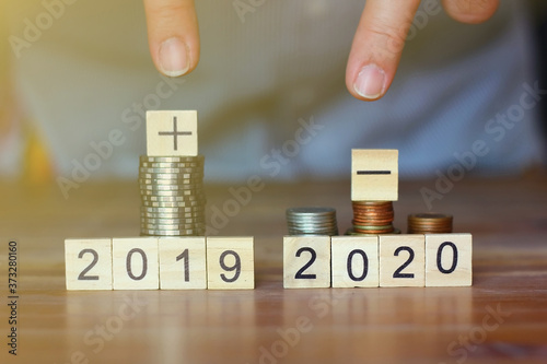 business man pointing his fingers to stack of coins  and plus sign,minus sign world economic.business concept.