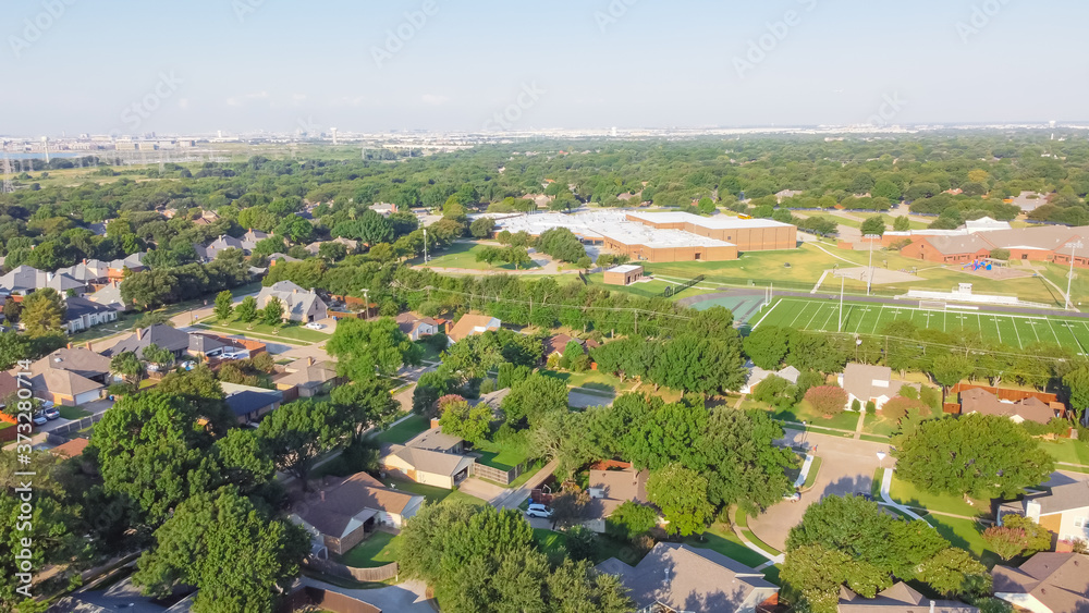 Aerial view residential neighborhood in school district with football field in near Dallas, Texas, USA