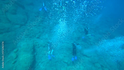 Fethiye, Turkey - 30th of July 2020: 4K Scuba divers below underwater wave hands

