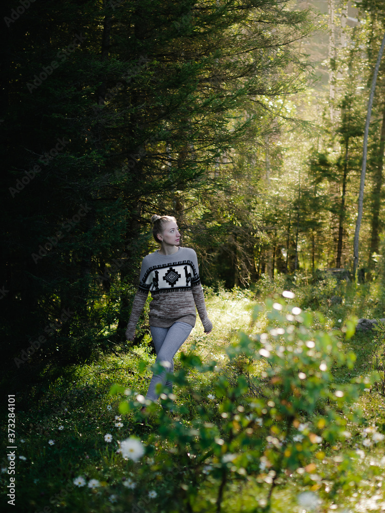 A young woman walks in the morning forest, enjoys the scent of flowers and rests in silence. Summer, spring, travel, vacation or relaxation concept. A young woman walks in the morning forest, enjoys the scent of flowers and rests in silence. Summer, spring, travel, vacation or relaxation concept.
