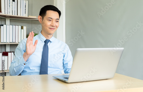 young asian businessman using computer to work via video call conference in office. business and technology concept photo