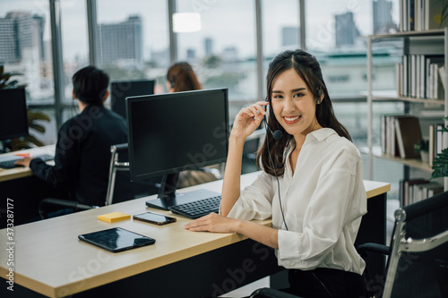 Asian woman customer support operator or call center with headset looking the camera and smiling.