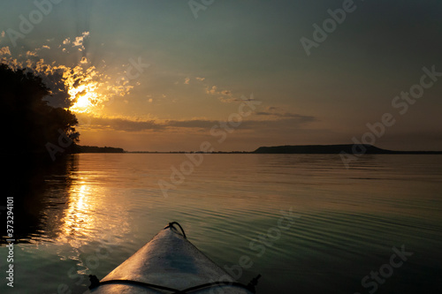 Kayaking at sunrise on a peaceful lake, plateau mountains in the distance