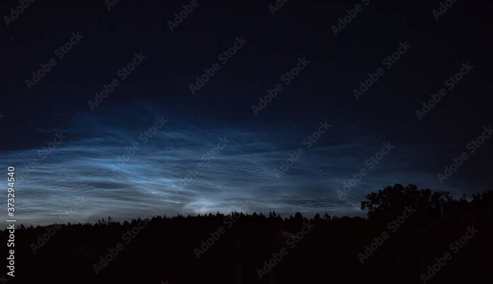 Noctilucent clouds high in the sky at midnight.