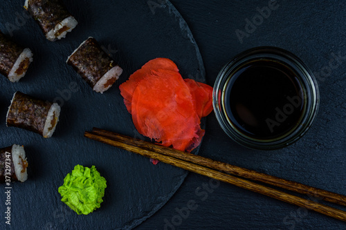 Sushi maki roll with tuna, wasabi and ginger on a slate board. Japanese food. Top view