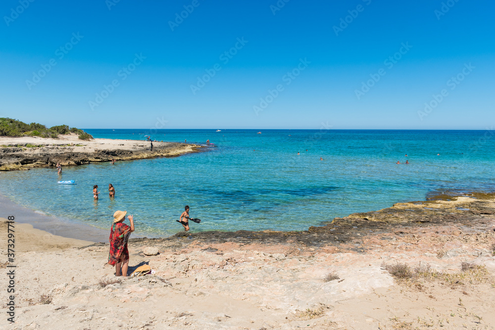 Wonderful Mediterranean coast beach in Puglia, South Italy, with bathers in crystal clear water
