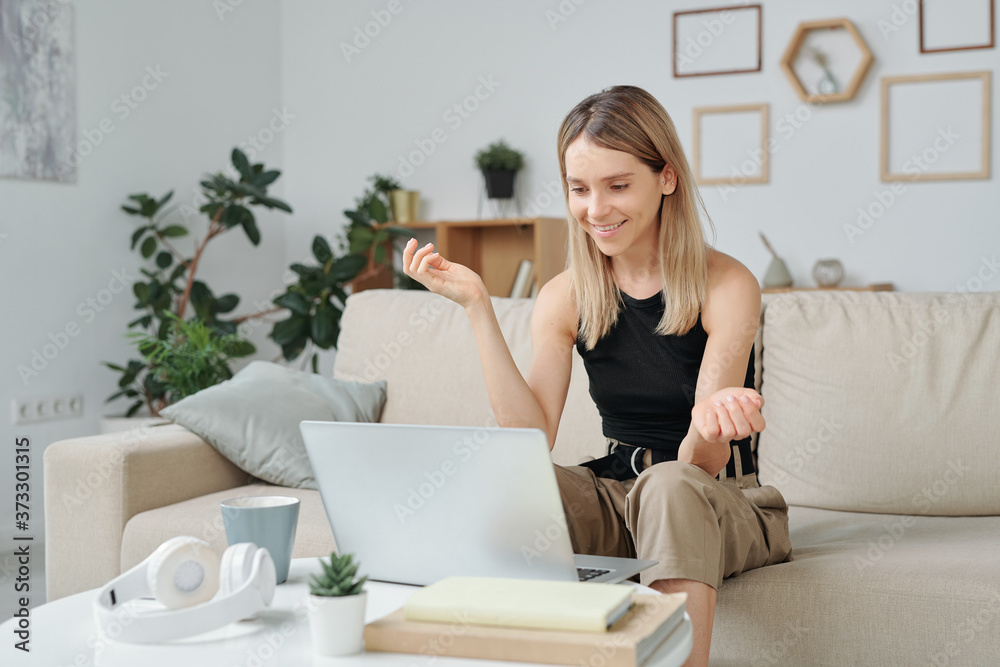 Blond woman in casualwear explaining something to her friend on laptop display Blond woman in casualwear explaining something to her friend on laptop display