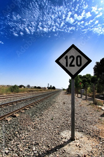 Speed sign limited to 120 km per hour next to train tracks