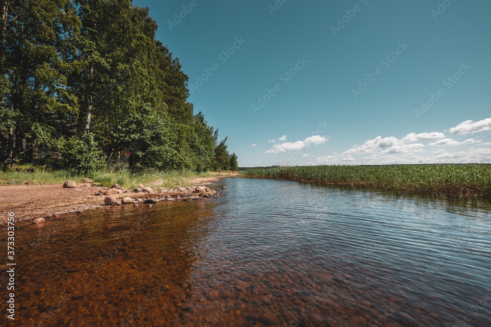 Huge stones on the river bank. Vuoksa river near Imatra in the Leningrad region, Russia. Coastline with birch, pine tree forest reflected in Vuoksa water, near Finland.