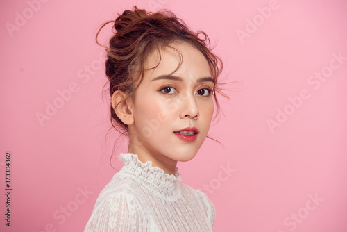 Portrait of young beautiful asian girl smiling looking at camera over pink background.