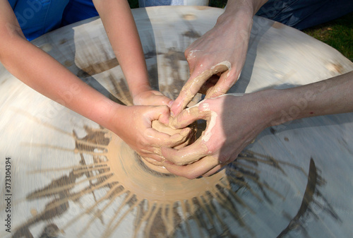 Teaching of wheel throwing. Potter hand correcting child s ones during shaping clay on a potter wheel photo