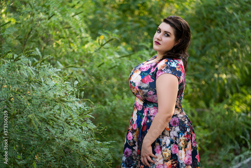 Plus size fashion model in floral dress outdoors, beautiful fat woman with beauty makeup and hairstyle