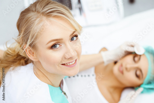 Professional beautician and young woman in beauty salon. Makeup artist touch customer skin with cotton pads, closeup. Cosmetology , facial, beauty and spa