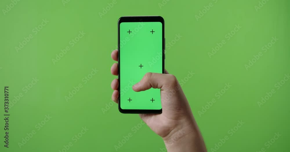 Close up of man's hand holding a smart phone with vertical green mock ...
