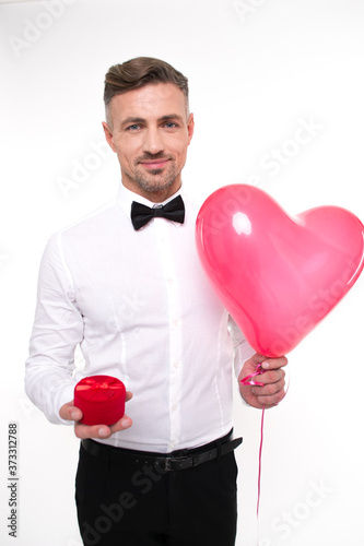  My love! Handsome young man holding red balloon and jewelry box and looking at camera with smile while standing against white background  © MARIIA