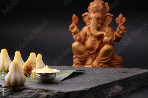 Modak- a traditional dish made on Ganpati festival in India. served with clarified butter. Ganesh idol at background photo