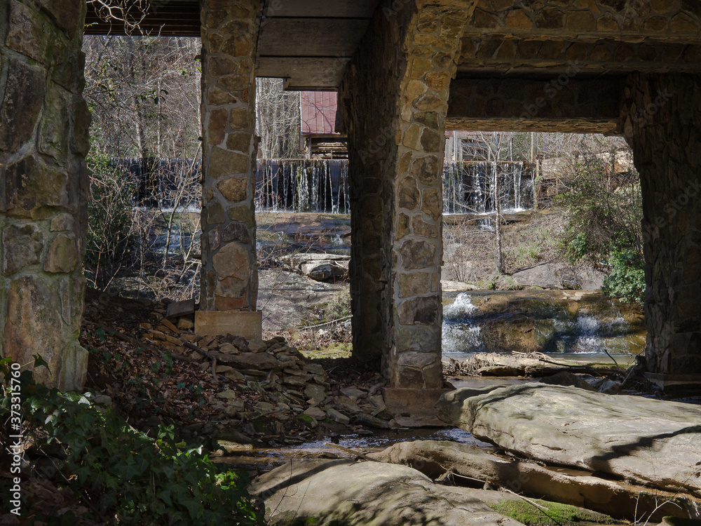 Waterfall flowing behind and under an old stone bridge abutment. Waterfall flowing behind and under an old stone bridge abutment.