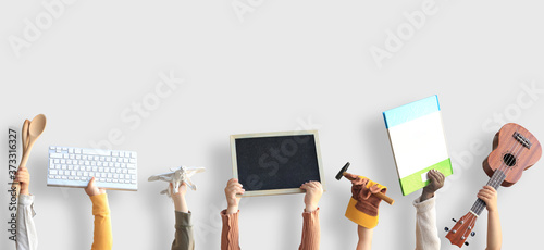 Children are holding books, toys, and a keyboard. Educational concept