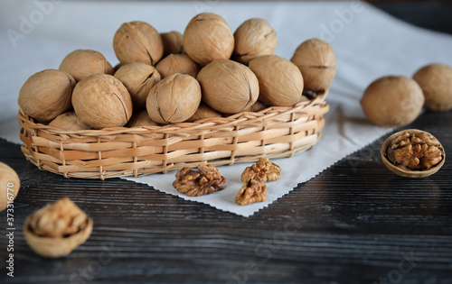 Inshell walnuts in a wicker bowl lie on the table on a linen napkin. Whole and peeled nuts, in the shell. Healthy snack. HLS. Close up