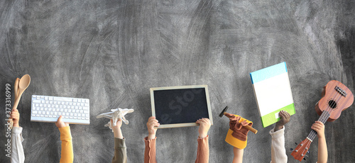 Children are holding books, toys, and a keyboard. Educational concept photo