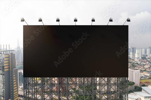 Blank black road billboard with Kuala Lumpur cityscape background at day time. Street advertising poster, mock up, 3D rendering. Front view. Concept of marketing to promote or sell services or ideas.