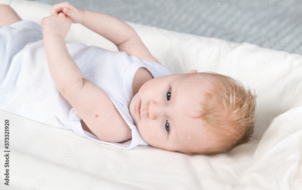 A beautiful newborn with traces of BCG vaccination-the TB vaccine-on his arm. The baby is lying on changing table and looks away