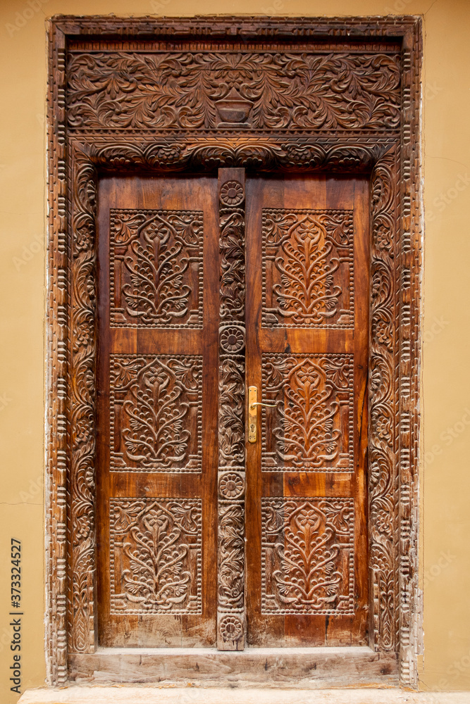 Brown traditional wooden carved Zanzibar doors in Stone Town, artwork of swahili culture, well preserved and renovated. 