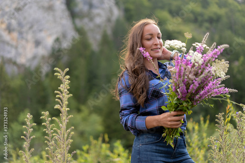 Beautiful middle age woman looking at wild flower bouquet harvested from nature.