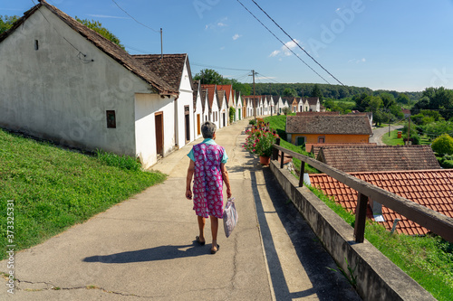 old citizen woman walking on the srteet of many colorful old traditional wine cellers in Villanykovesd in a hungarian wine region called Villany photo