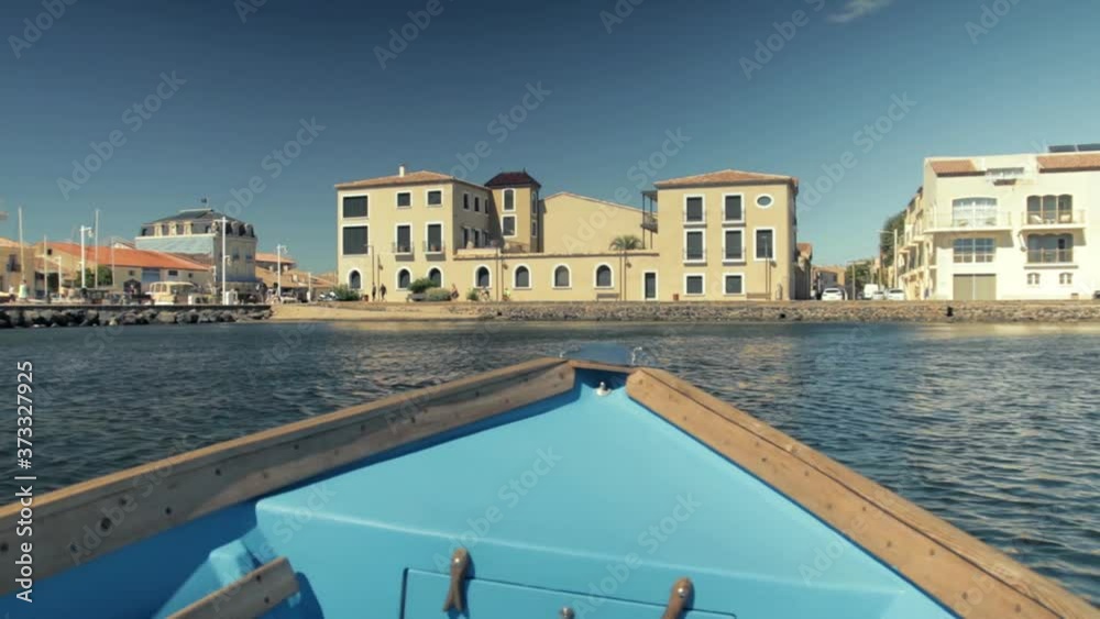 vue d'un batiment rénové à Marseillan village sur la cote, depuis une barque qui avance sur la lagune de Thau.